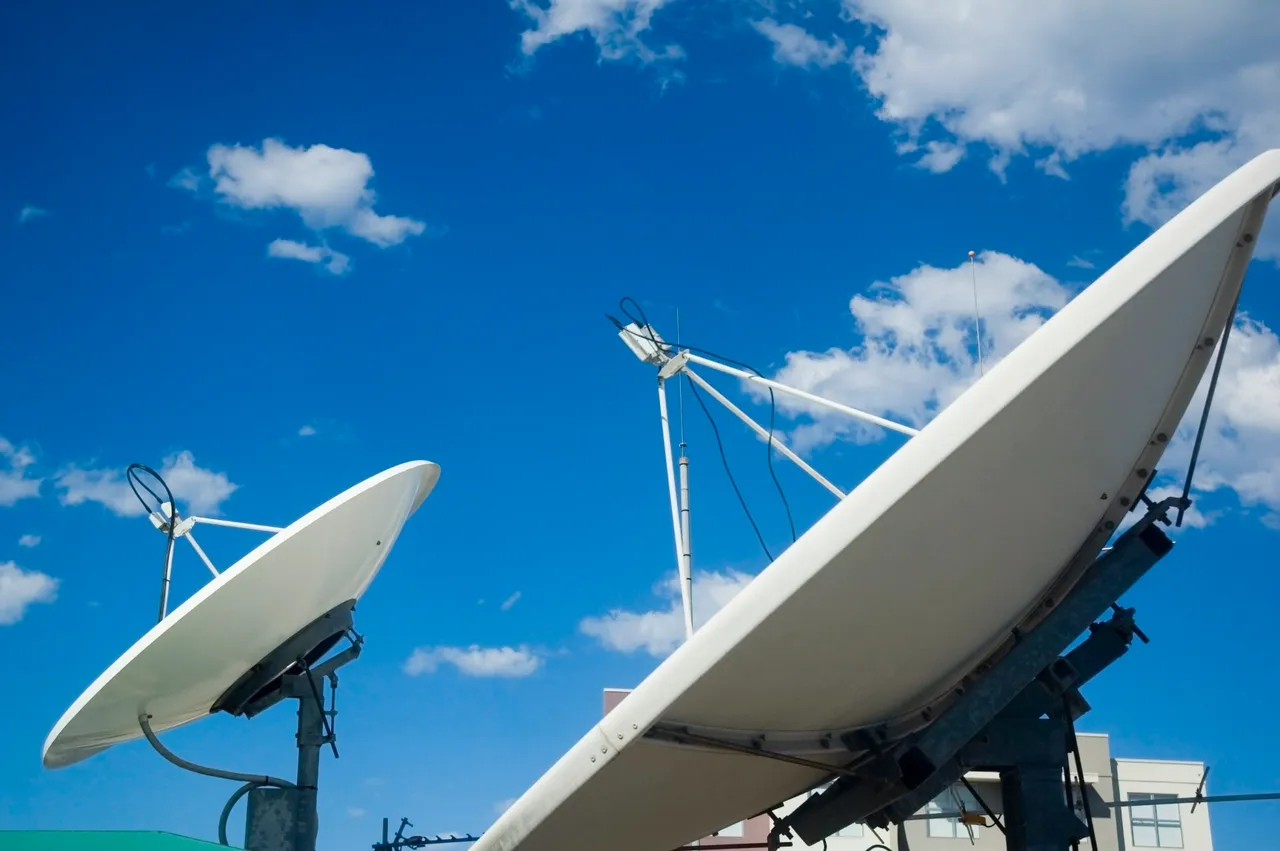 Two communications satellite dishes against a blue sky